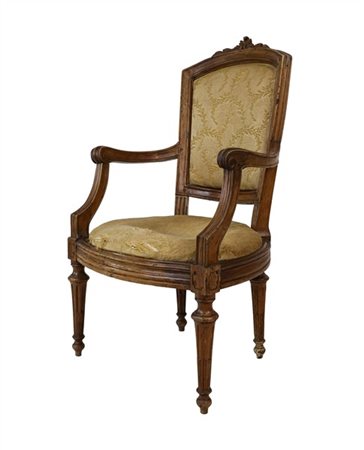 Poltrona in noce con schienale decorato da cimasa intagliata e bordure scanalat