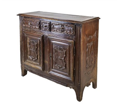 Credenza a due ante e tre cassetti in noce intagliato a volute mistilinee. Piem