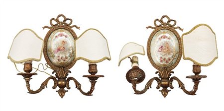 Coppia di appliques a due luci in bronzo con bracci a volute e placca ovale in