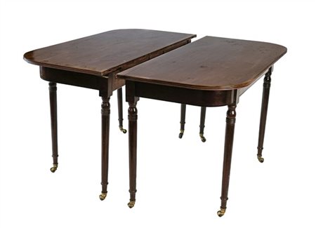 Due mezzi tavoli in mogano e altri legni con gambe tornite su ruotine, piano co