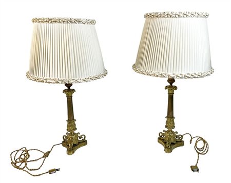 Coppia di candelieri in metallo dorato con fusto a colonna su base tripode e so