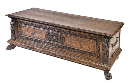 Cassapanca in noce con fronte decorato da intagli a tralci di foglie, montanti