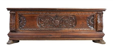 Cassapanca in noce con fronte decorato da intagli a volute e scudo con stemma a