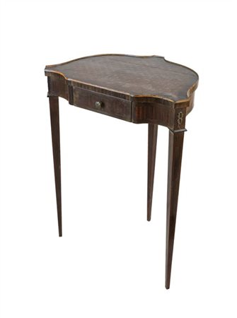 Gueridon in legni vari con piano sagomato ed alte gambe rastremate, un cassetto