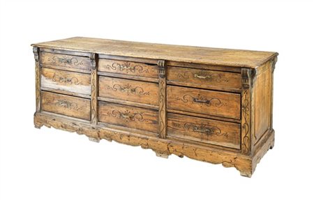 Bancone da centro con fronte a nove diversi cassetti e montanti decorati da sca