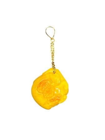 Pendente in oro con ambra intagliato a forma di seme di pesco, elemento che...