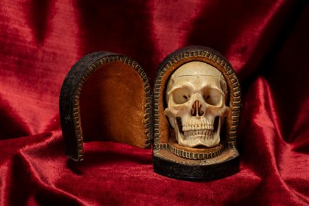 Memento mori raffigurante teschio in avorio intagliato e traforato, calotta cranica removibile e mascella con movimento a molla. Entro custodia in pelle impressa a motivi fogliacei. Nord Europa, secolo XIX