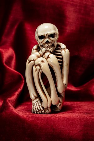 Okimono in avorio raffigurante scheletro accovacciato realisticamente intagliato. Giappone, inizio secolo XX