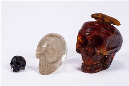 Tre memento mori di cui uno in ambra scolpita raffigurante teschio sormontato da salamandra, uno in cristallo di rocca ed uno in argento