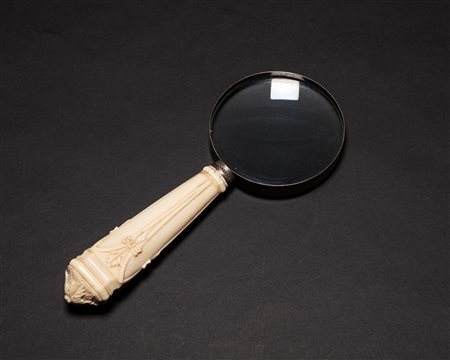 Lente di ingrandimento con manico in avorio intagliato a nastri e foglie d'acanto. Secolo XIX/XX