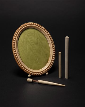 Lotto in avorio composto da una cornice portafoto di forma ovale a bordo perlinato, due bocchini per sigaretta ed una boccetta porta profumo con applicatore. Secolo XIX/XX