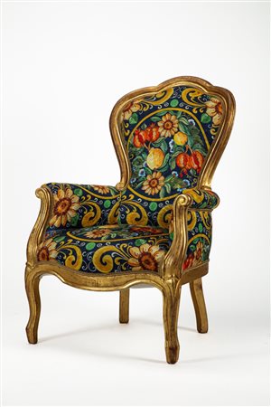 Poltrona di forma mossa in legno intagliato e dorato con braccioli terminanti a ricciolo. Secolo XIX.