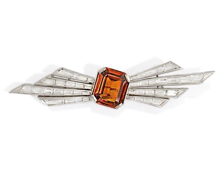 SPILLA SPILLA. In platino, a fiocco centrata da gemma arancio-brunita taglio...