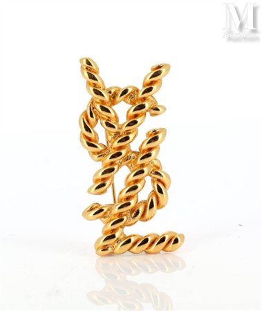 YVES SAINT-LAURENT Broche en métal doré à décor du monogramme YSL, les...