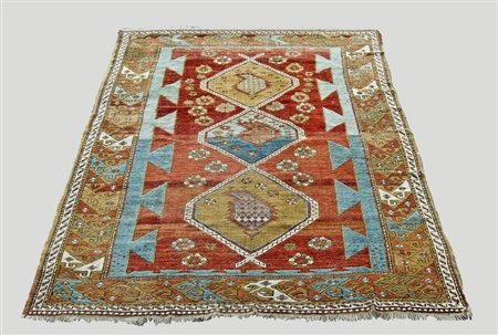 TAPPETO CAUCASICO fondo ruggine, campo a tre medaglioni tra motivi geometrici...