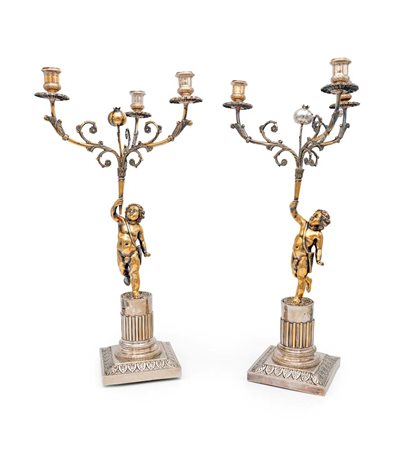 Coppia di candelabri a tre fiamme in argento e argento dorato con putti,...