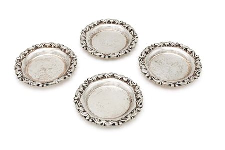 Quattro piattini da pane in argento con orlo percorso da volute vegetali in...