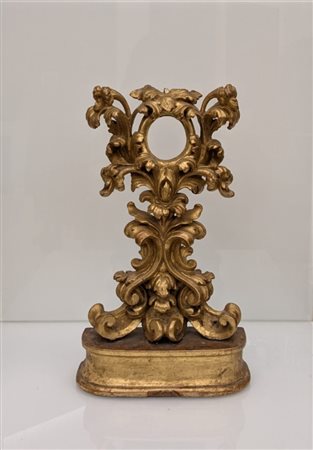 Manifattura Italiana della Fine del XVIII Secolo  
Reliquiario a ostensorio in legno di bosso dorato e riccamente intagliato con girali fogliati e fiori, poggiante su una base 
 Cm. h 37 x 22 x 7