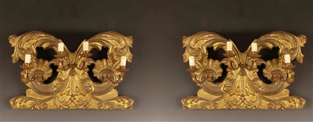 Coppia di appliques a quattro luci in metallo dorato, poggianti su basi in...