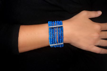 Bracciale a fascia in oro 585 (14 KT) con granati e pietre sulla susta e lungo le 3 bande di sostegno che intervallano le 7 fila di grani in pasta di zaffiro