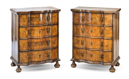 Coppia di mobiletti a quattro cassetti lastronati in noce, fronte mosso, piedi