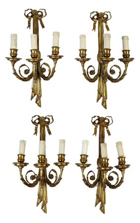 Gruppo di quattro appliques a tre luci in metallo dorato cimate da nastro trafo