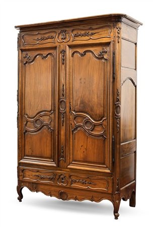 Armadio in noce a due ante pannellate e un cassetto alla base, decori a scanala