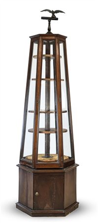 Vetrina da centro in noce a sezione esagonale con sportello alla base e parte s