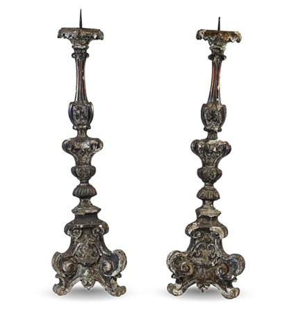 Coppia di candelieri in legno intagliato e argentato con decoro a volute su bas