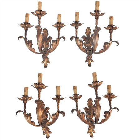 Gruppo di quattro applique in lamierino dorato a tre luci con decoro fogliato (