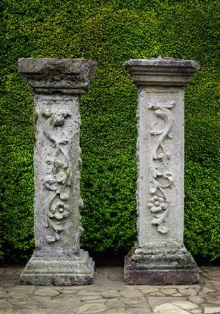 Lotto di due pilastrini decorati in rilievo con fiori e frutti, basi squadrate.