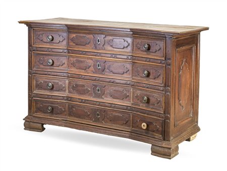 Cassettone in noce con fronte mosso a quattro cassetti con rilievi mistilinei,