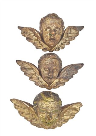 Gruppo di tre teste d'angelo in legno intagliato e dorato a mecca. Secolo XIX (