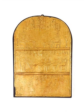 Calco centinato in gesso dorato con rilievi a figure egizie su supporto ligneo.