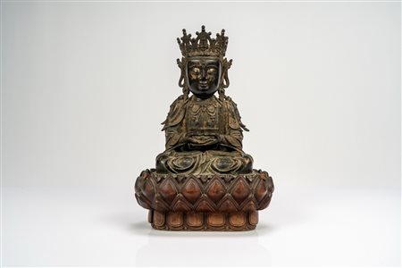 Guanyin in bronzo cesellato, con tracce di doratura, su base lignea a fiori di loto di epoca successiva. Cina, dinastia Ming, secolo XVII