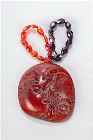 Ciondolo in ambra scolpito con uccellino su ramo fiorito. Cina, inizi secolo XX.
