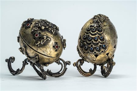Due uova con coperchio in argento e cabochon una decorata a rilievo con pavone e l’altra con putti e ghirlande di fiori. Russia, fine XIX secolo