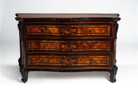 Cassettone lastronato in noce e radica di noce con fronte mosso a tre cassetti profilati da cornici in legno ebanizzato. Montanti a lesena terminante  […]