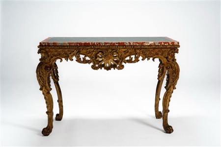 Console in legno intagliato con gambe mosse ornate da motivi fogliacei, volute e piedi ferini, fregio traforato centrato da motivo a conchiglia. Piano […]