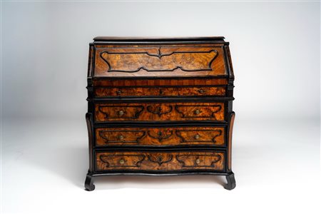 Cassettone a ribalta lastronato in noce e radica di noce a tre cassetti più uno a mezza altezza e calatoia celante sei tiretti. Decorato a cartelle sa […]