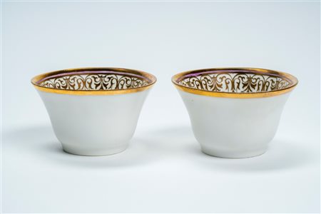 Coppia di chicchere in porcellana profilata in oro. Francia, metà secolo XIX.