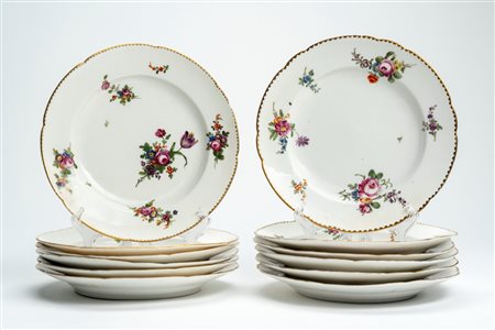 Dodici piatti piani in porcellana a bordo mosso e dorato con decoro policromo al mazzetto e rametti di fiori sparsi. Probabilmente Francia, fine secol […]