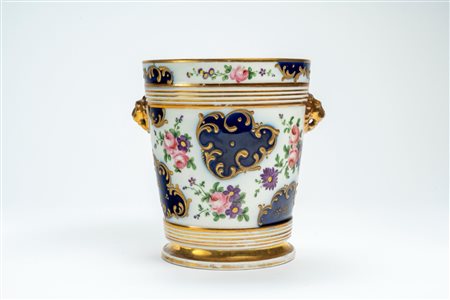 Porta vaso biansato in porcellana decorata a bouquet di fiori e riserve blu con rocaille dorate a rilievo. Probabilmente Francia, secolo XIX