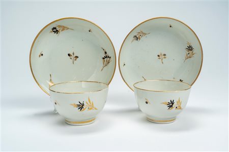Coppia di tazze con piattino in porcellana decorata in oro e nero a rametti di fiori sparsi. Chamberlain Worcester, fine secolo XVIII
