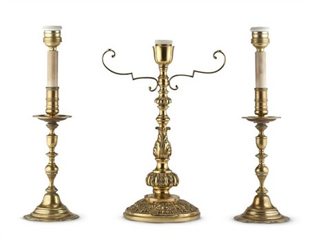 Tre candelieri in metallo dorato di diversa forma e decoro elettrificati con pa