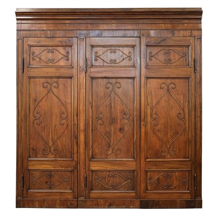 Fronte di armadiatura a muro a tre ante pannellate in noce con decorazione a vo