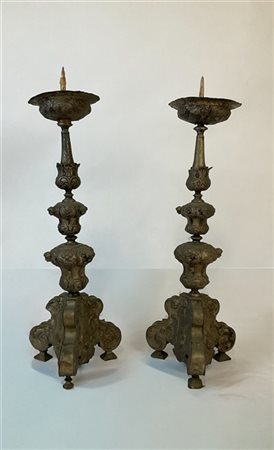 Coppia di candelieri in legno rivestito in metallo argentato inciso e cesellato