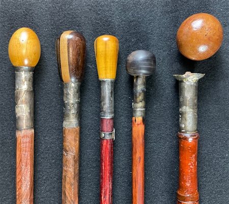 Lotto di cinque bastoni da passeggio con fusti in legni differenti, ghiere in a