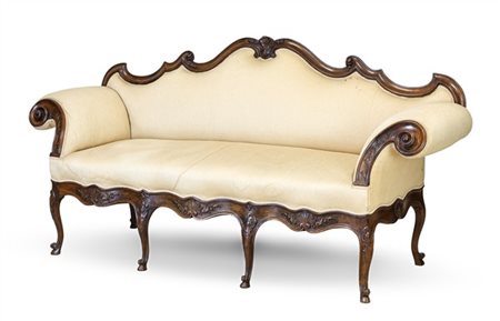 Divano a orecchioni in noce intagliato con schienale sagomato a volute contrapp