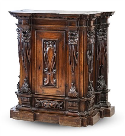 Stipo in noce intagliato a struttura architettonica con anta frontale pannellat